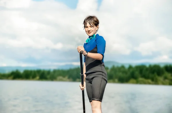 アクティブティーンの女の子は 川や湖 自然の背景にアップボードを漕ぐ アクティブな健康的なスポーティライフスタイル 高品質の写真 ロイヤリティフリーのストック写真