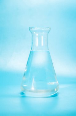 Cam bir laboratuvar şişesinde su kabarcıkları olan berrak bir sıvı. Mavi arka planda bir şişe izolasyon. Yüksek kalite fotoğraf