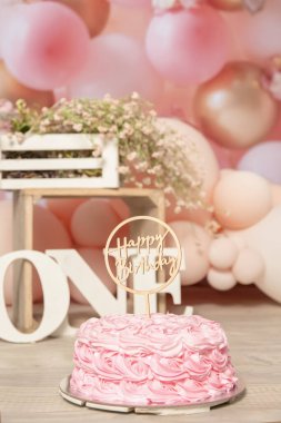 pink and white decoration for a 1st birthday cake smash studio photo shoot with balloons, paper decor, cake and topper. High quality photo