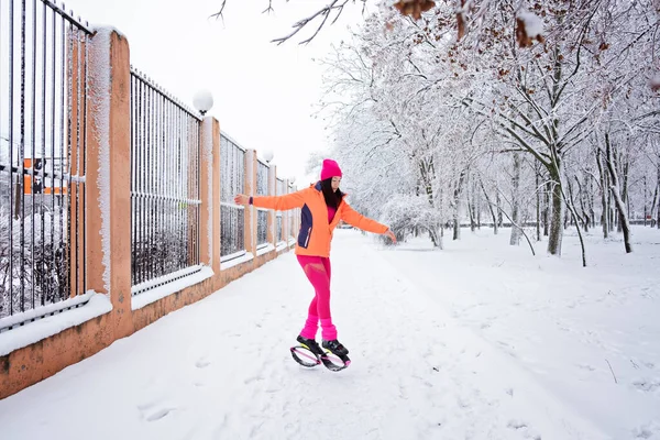 Winter workout, exercising in cold weather. Winter fitness Trening kangoo jumps. Sporty woman in sportswear and kangoo jump shoes jumping in winter snowy park, forest