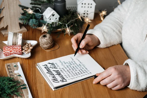 圣诞桶清单 圣诞清单倒计时 为准备寒假你需要做的任务 女人带着礼物写在桌上的笔记本圣诞纸桶上 — 图库照片