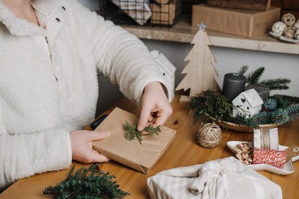 stock image Christmas Zero waste eco friendly reuse wrapping gifts process. Woman wrapping Christmas Zero waste reusable craft paper sustainable gifts in craft paper with green leaves on table at home.