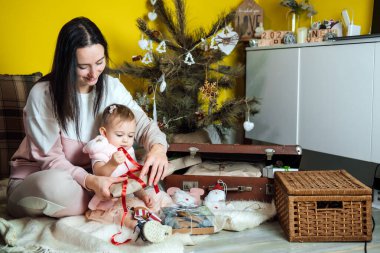 Boks günü ve Noel hediyelerini açma günü. Sevimli küçük bebek kız ve anne evdeki Noel ağacının yanındaki hediye kutularını açıyor. Mutlu Noeller ve mutlu yıllar..
