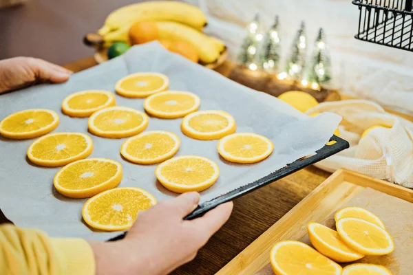 How to Dry Orange Slices for Eco friendly zero waste Holiday Decor. Close up Process of Drying Orange Slices in Oven. Woman cutting slices of orange and citrus fruits for drying in oven in kitchen.