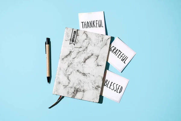 如何实践感恩之心 在开著的笔记本上写着感谢的话 注意欣赏美好的事物 表达对自己的感激之情 在蓝色背景的打开的笔记本中祝福 — 图库照片