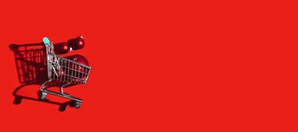 Boże Narodzenie Wózki Sklepowe Czerwonymi Ozdobami Ozdobne Kulki Czerwonym Tle — Zdjęcie stockowe