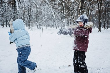 Çocukların karda oynayabileceği eğlenceli oyunlar. Çocuklar ve aile için açık hava kış aktiviteleri. Mutlu çocuklar kış karlı parkında eğleniyor, koşuyor, birlikte kartopu oynuyorlar..