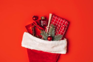 Noel hediyeleri aile, arkadaşlar, iş arkadaşları, komşular için. Kırmızı arka planda hediyeli Noel Baba şapkası. Noel hediyeleri ve kırmızı arka planda Noel Baba şapkası. Xmas hediye fikirleri