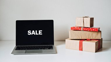 Online Sale, Holidays online alışveriş, E-Commerce. Dizüstü bilgisayar ekranını kelime satışı ve hediye kutularıyla beyaz masada aç