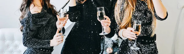 Web banner Cheers, toast with champagne. Friends celebrating Christmas or New Year eve party. Faceless Group of people cheering with champagne glasses festive interior in the background.