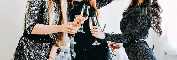 Web banner Cheers, toast with champagne. Friends celebrating Christmas or New Year eve party. Faceless Group of people cheering with champagne glasses festive interior in the background.