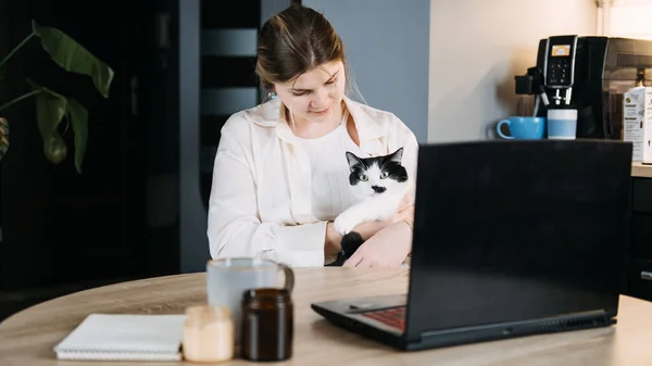 Veterinary Telemedicine Services, Online veterinarian services for virtual pet care. Young woman with cat and using laptop for video call meeting and telemedicine with veterinary from home.