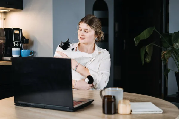 Veterinary Telemedicine Services, Online veterinarian services for virtual pet care. Young woman with cat and using laptop for video call meeting and telemedicine with veterinary from home.