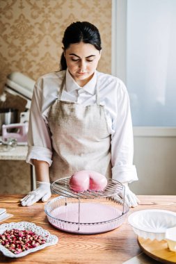 Female baker make Perfect custom pink heart shape cake in kitchen Bakery. Online Cake Store. custom cake order for Every Special Event.