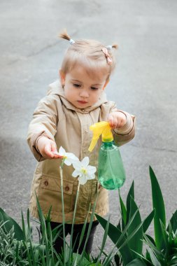 Çocuklar ve doğayla bağ kurmak. Çocuklara bitkilerle ve çevreyle ilgilenmenin önemini öğretmenin değeri. Yaşlı kadın büyükanne ve çiçekleri sulayan küçük kız..