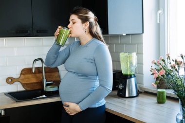 Demir eksikliği, anemi, hamile bir kadın için alkollü içecek tarifleri. Hamile kadın yeşil vitamin kokteyli hazırlıyor blenderla ve mutfakta içiyor.
