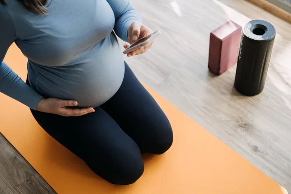 stock image Pregnancy Workout Apps, Pregnancy Exercise Apps. Prenatal and Postnatal Workout, Pregnancy Wellness and Yoga Workouts in cell phone. Pregnant woman looking for Workout in phone.