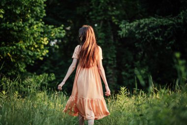 Dünya Ayı 'nı, Dünya Günü' nü kutlayın. Doğada zaman geçirmek. Doğayla bağlantı kurmak iklim kaygısını hafifletmenin bir yoludur. Genç bayan, kız dışarıda yürüyor ve doğanın tadını çıkarıyor..