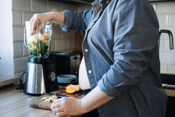 美味佳肴和美味佳肴抗恶心 晨吐光滑 怀孕妇女在厨房里用搅拌机从各种水果和蔬菜中配制绿色维生素冰沙 — 图库照片