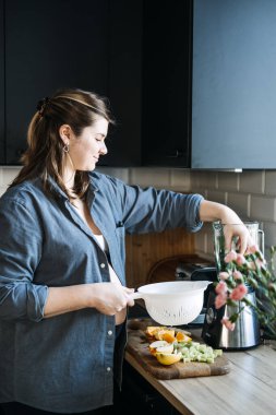 Meyve suyu ve hamilelik bulantısı için yiyecek. Mide bulantısı önleyici sabah içeceği. Hamile kadın mutfakta blender ile çeşitli meyve ve sebzelerden yeşil vitamin smoothie hazırlıyor..