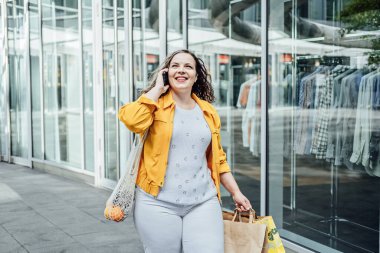Büyük bir göbek için nasıl büyük beden bir kapsül dolabı yapılır. Temel Kapsül Giysi Giysileri Styling. Alışverişte stil sahibi kadının açık hava portresi..