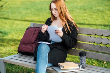 Öğrenci Kredisi Ödeme Seçenekleri. Federal Öğrenci Kredileri davasının artıları ve eksileri. Gözlüklü, dizüstü bilgisayarı ve açık havada kitap okuyan genç kız..