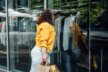 Büyük bir göbek için nasıl büyük beden bir kapsül dolabı yapılır. Temel Kapsül Giysi Giysileri Styling. Alışverişte stil sahibi kadının açık hava portresi..