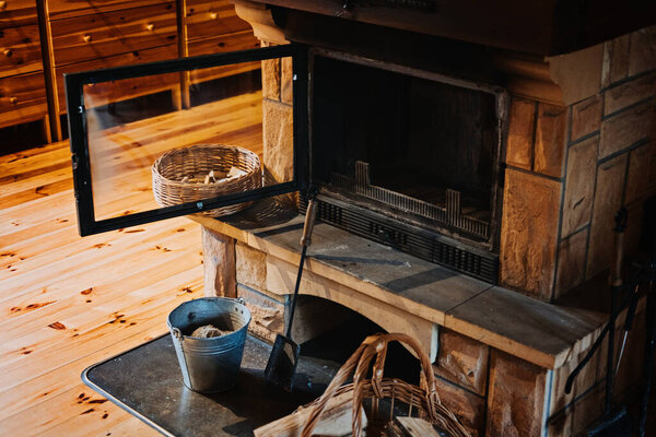 How to Remove Wood Ashes In Fireplace, How To Properly Clean Ashes Out Of Home Fireplace. Cleaning fireplace with open tray. Fireplace, wicker basket for firewood, pile of logs for a fire.