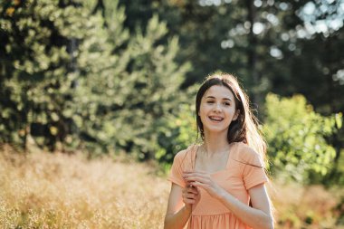 Mutluluk, heyecan, neşe, umut ve ilham gibi olumlu duygular mutlu ve sağlıklı yaşam için hayati önem taşır. Doğada gülümseyen genç bir kadının açık hava portresi..