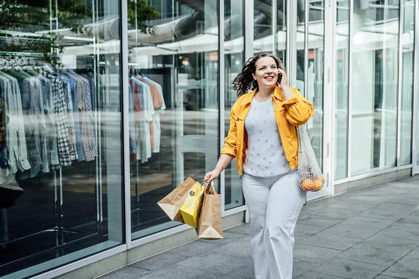 stock image Cheerful happy plus size curvy woman talking on phone outdoors. Outdoor portrait of happy smiling candid plus size woman with cell phone on city street.