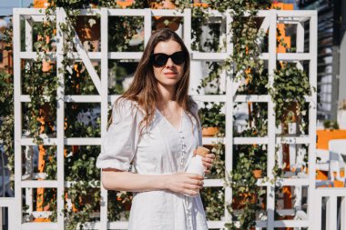 Yaz boyunca vücudun ne kadar suya ihtiyacı olursa, İçmek için kaynaşmış suyu çıkar. Daha fazla su içmek için yaz tavsiyeleri. Güneşli yaz şehrinde elinde su şişesi olan bir kadın..