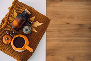 Sonbahar sıcacık evi. Battaniye, mumlar, sonbahar yaprakları, beyaz masadaki kahverengi yatakta bir fincan kahve. Soğuk mevsim sabah kahvesi, rahatlatıcı hayat konsepti.