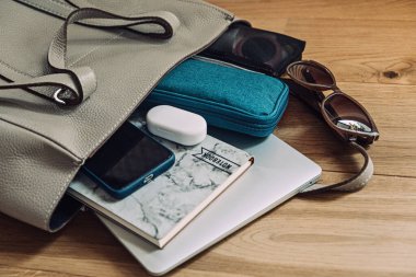 Seyahat için gerekli eşyalar toplanır, eşyalar taşınır. Uçak Taşımacılığı için paketleme listesi. Dizüstü bilgisayarı, not defteri, gözlüğü, kulaklığı, makyaj malzemesi olan kadın valizi..