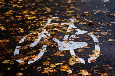 Kaldırımda bisiklet için imza, sonbahar yapraklarıyla kaplı bisiklet yolu. Sonbahar aktiviteleri, mevsimsel değişiklikler, açık hava egzersizleri, doğa yolları, sonbahar bisikletleri..