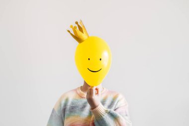 Yeni yıl partisi eğlence etkinliği, yüzsüz bir kadın ve beyaz üzerinde altın taç olan gülümseyen sarı balonla minimum konsept. Yeni yıl, doğum günü partisi mezuniyeti yaratıcı minimum özgeçmiş.