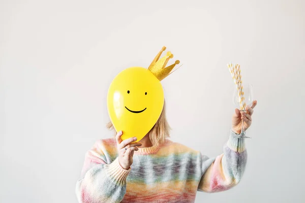 New year party time fun celebration event minimal concept with faceless woman and smiling yellow balloon with golden crown on white. New year, birthday Party graduation creative minimal background.