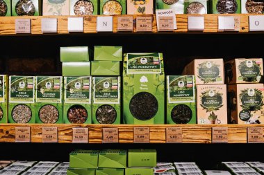 Marketteki raflarda bitki çayı çeşitleri. Organik ürünler mağazasının raflarında doğal sağlık ürünleriyle ilgilenen müşteriler için düzgünce sergilenen çeşitli organik bitkisel çaylar.
