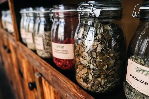Glass Jars of Assorted Organic Freeze-Dried Foods on Wooden Shelf. A rustic wooden shelf with glass jars filled with various dried fruit, Raspberries, herbs and seeds, showcasing an organized pantry