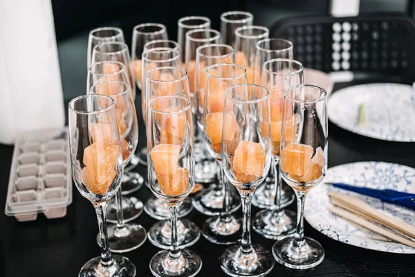 Elegant Champagne Glasses with Sorbet for Catering Event. Rows of champagne glasses filled with refreshing orange sorbet, prepared for a sophisticated catering event or celebration