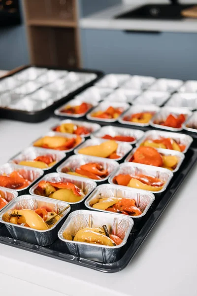 Pre-portioned Gourmet Roasted Bell Peppers in Trays. Close-up view of vibrant roasted bell peppers portioned in aluminum trays, prepared for a catered event or meal service