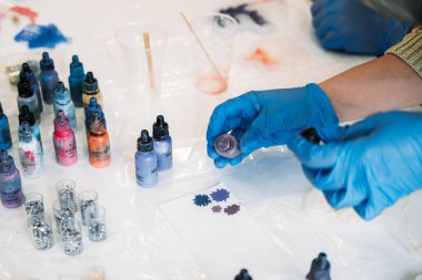 Bir bireyin epoksi reçine sanatı yapma, ölçme ve dökme tekniklerini vurgulama sürecinde olduğu bir el sanatları oturumunun ayrıntılı bir görünümü.