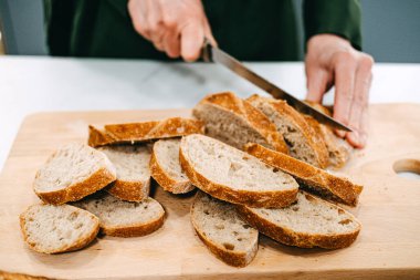 Taze pişirilmiş ev yapımı ekmek, lifli ve tahıllı, tahta bir tahta üzerinde kağıt bir torbayla sergileniyor..