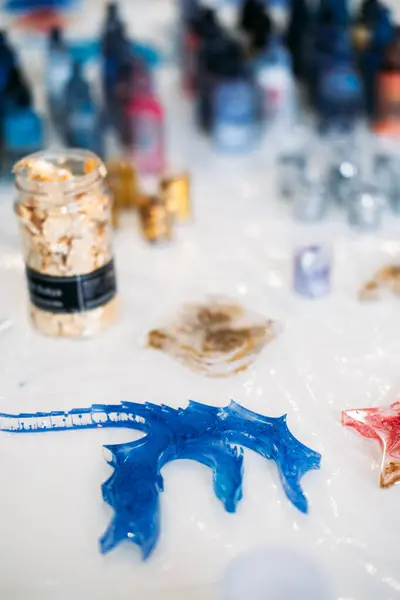 A vibrant blue epoxy resin dragon on a worktable, amidst crafting tools and pigment bottles, illustrating the creative process of resin art.
