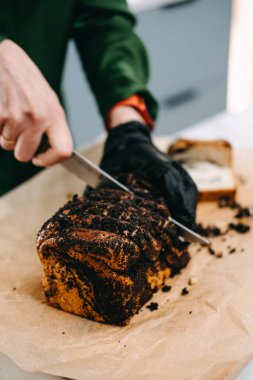 Yeni pişmiş haşhaş tohumu kesen ellerin yakın çekimi, sıcak ve nostaljik duyguları geri getiren geleneksel bir ikram..