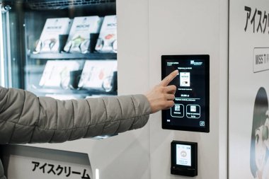 Müşteri, otomatik perakende satış kioskunun dokunmatik ekranından çeşitli ürünler sunan bir ürün seçer, alışverişte self-servis teknolojisi. Varşova, Polonya - 19 Mart 2024