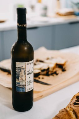 Bir şişe tatlı şarap dilimlenmiş mermer bir pastaya eşlik etmeye hazır. Tatlı eşleşmesi ya da tatlı bir mutfak düşkünlüğü için ideal. Varşova, Polonya - 02 Mayıs 2023