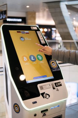 Bir kişi, şifreli para aktarımları için dijital ekrandan seçenekler seçerek Bitcoin ATM kiosk ile etkileşim içindedir.