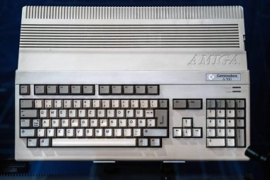 Klasik Commodore Amiga A-500 bilgisayarı mavi arka planda, bilgisayar tarihinin simgesel bir parçası..