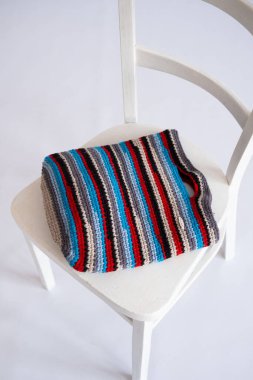 Detailed view of a striped crochet bag featuring vibrant colors and with unbranded text Handmade on the tag, representing upcycled fashion trends. clipart