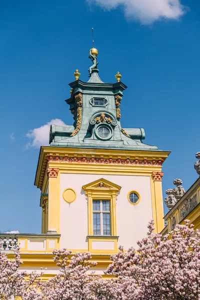 stock image The Museum of King Jan IIIs Palace at Wilanow, Warsaw, highlights stunning Baroque architecture with ornate details. The palace is surrounded by a well-maintained garden, featuring blooming trees